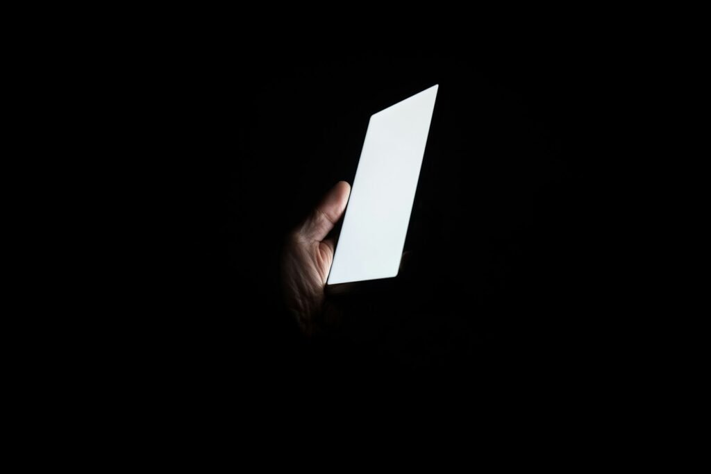 Mano sosteniendo un smartphone de noche, mensajeria automatizada 24/7